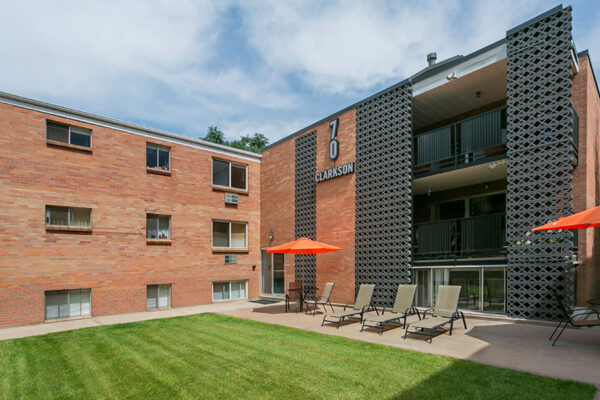 70 Clarkson apartment courtyard with lounge chairs, umbrellas and lawn overlooked by apartment balconies.