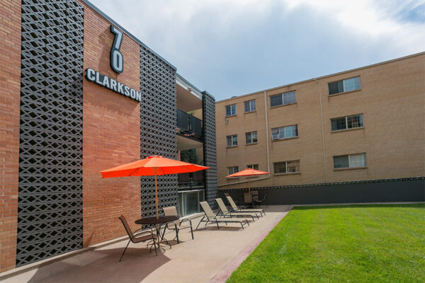70 Clarkson apartment courtyard with lounge chairs and lawn overlooked by apartment balconies.