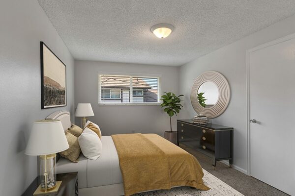 Bedroom with rug, bed with plush headboard, artwork and window.