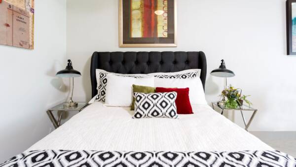 Bedroom with bed with plush headboard, modern metal side tables with lamps, and framed wall art.