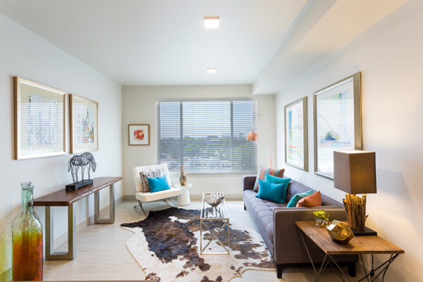 Living room with wood floor, plush seating, modern furniture, artwork, and large window.