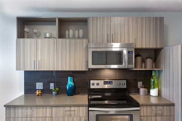 Kitchen with wood cabinets, stone counters, stainless steel appliances, and tiled backsplash.