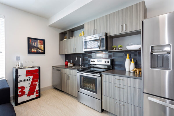 Studio kitchen with wood cabinets, stone counters, and stainless steel appliances.