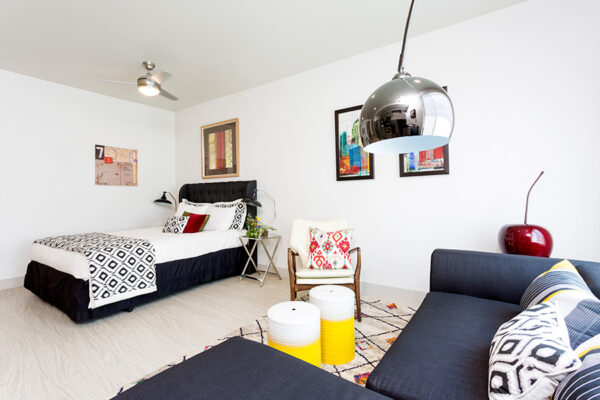 Studio living space with plush sectional, modern chair, and platform bed.