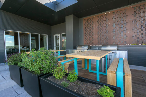 Outdoor patio with tall bar tables, built in BBQ grills, and geometric wall decor.