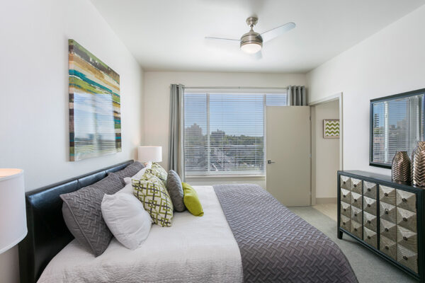 Bedroom with carpet, large plush bed, chic dresser, artwork, and large window.