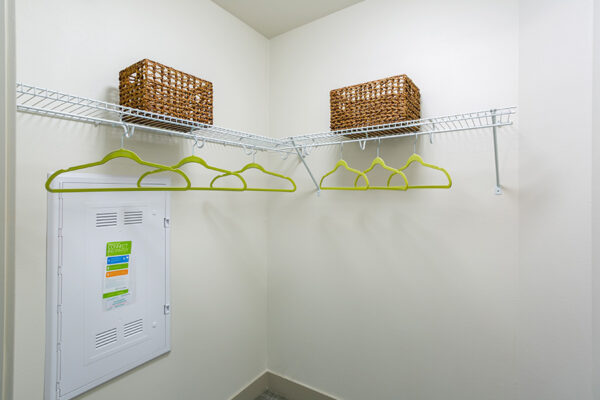 Walk in closet with wire shelves, hangers, and wicker storage boxes.