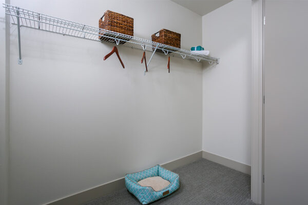 Closet with wire shelves, wicker storage boxes, and plush dog bed.