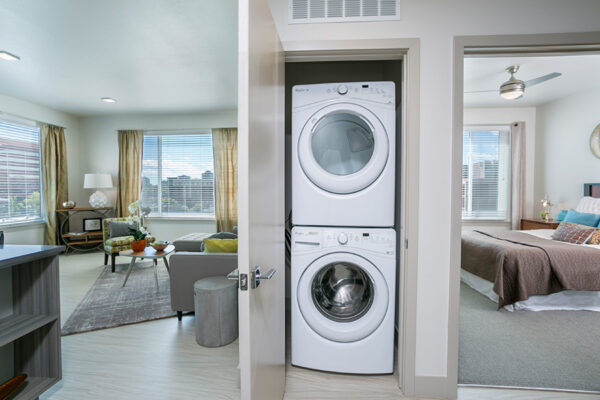 Apartment hallway and laundry closet with washer and dryer and entrances to living room and bedroom.