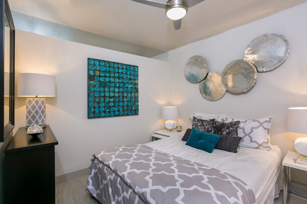 Bedroom with wood floor, large plush bed, wood furniture, and large wall art.