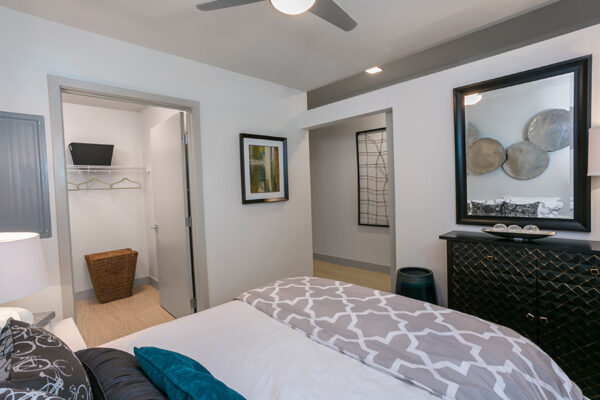 Bedroom with large plush bed, wood furniture, ceiling fan, and door to closet.