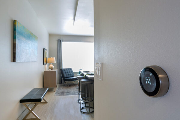 Apartment hallway into living room with detail of Nest thermostat.