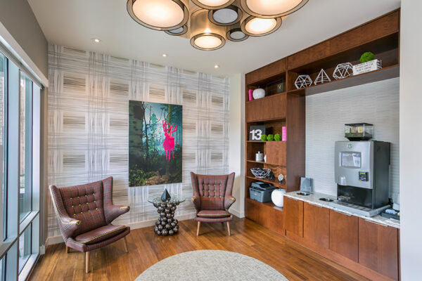 Lounge with coffee machine, shelves with decor, eclectic chairs and colorful artwork.