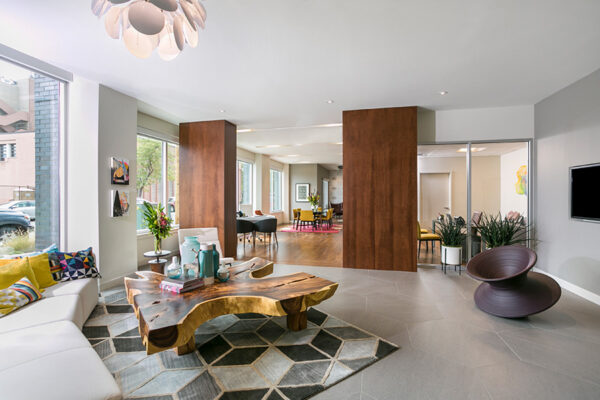 Lounge with geometric tile floors, large live edge wood table, comfortable sectional couch, and large windows.