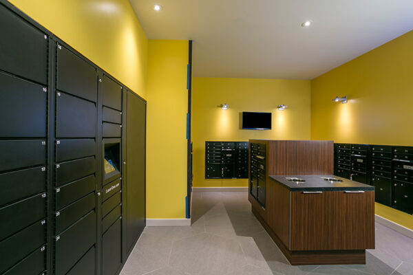 Mail room with bright yellow walls, mailboxes and parcel lockers.