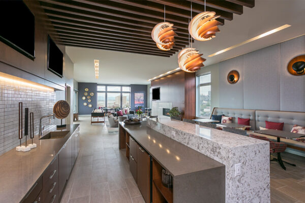 Community kitchen with stone bar top, comfortable booth seats, exposed beams, and decorative chandeliers.