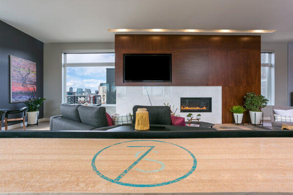 Detail of shuffleboard table with 7 S logo in front of wall with TV and fireplace.