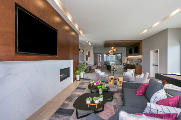 Lounge with large plush sectional, modern coffee tables, wall mounted TV and fireplace.