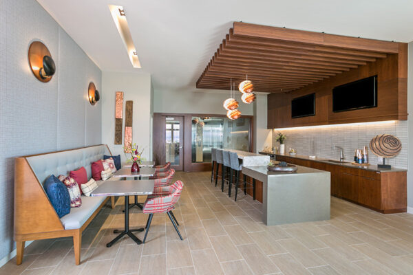 Community kitchen with bench tables, stone bar top, and wall mounted TVs.