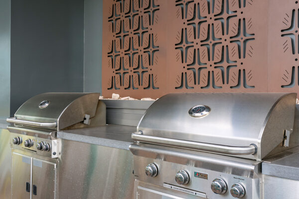 Detail of built in BBQ grills with decorative metal wall art behind.