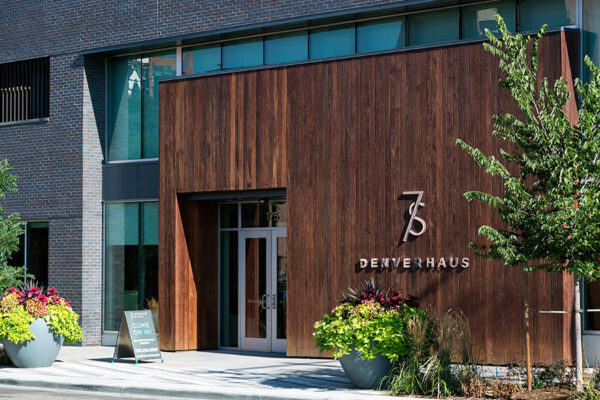 Lobby entrance of 7 S Denver Haus with wood panel and metal monument sign.