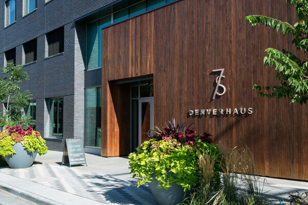 Lobby entrance of 7 S Denver Haus with wood panel and metal monument sign.