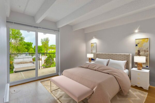 Bedroom with rug, large bed, bedside tables with lamps, and door to balcony.