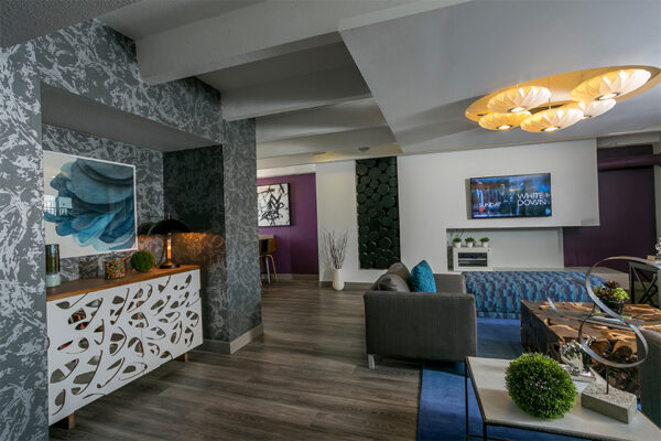 Lounge with plush furniture, colorful eclectic decor, and wall mounted TV.