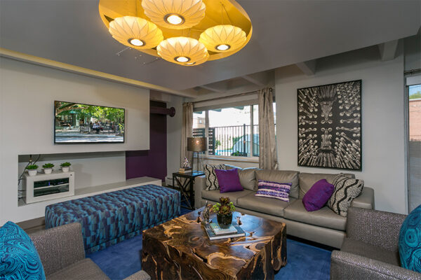 Lounge with plush furniture, colorful eclectic decor, and wall mounted TV.