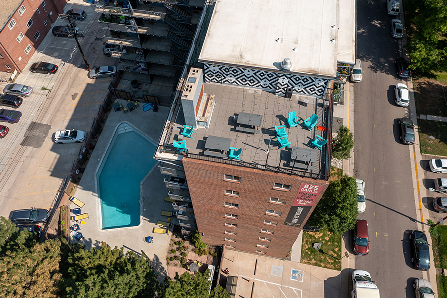 Aerial view of 825 Dahlia apartments with brick construction, angular pool, and rooftop patio.