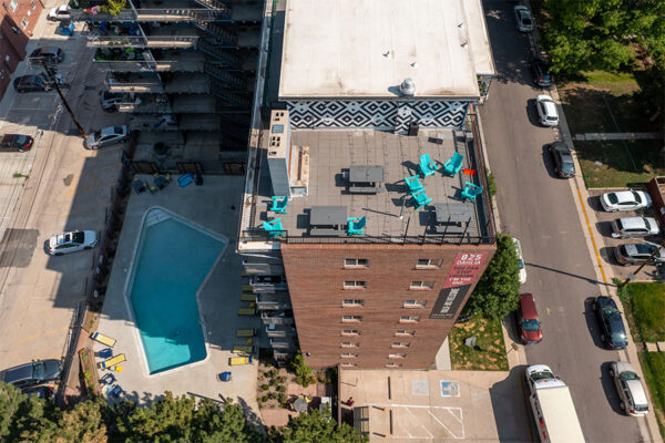 Aerial view of 825 Dahlia apartments with brick construction, angular pool, and rooftop patio.