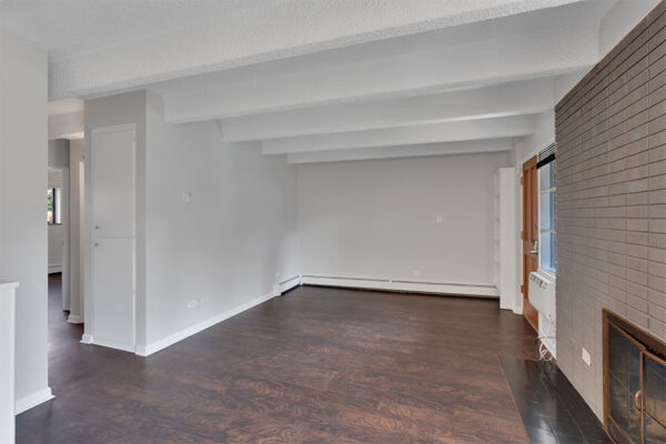 Living area with wood floor, baseboard heaters, grey walls, and brick accent wall with fireplace.