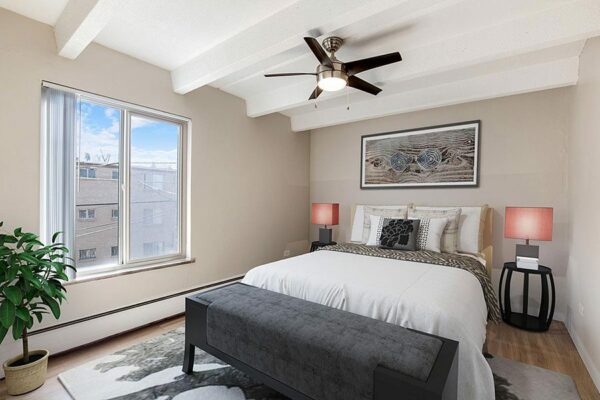 Bedroom with plush bed, large rug, bedside tables with lamps, and large window.