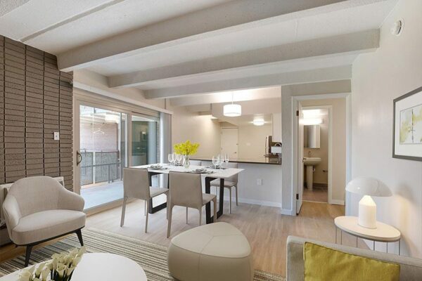 Kitchen and living area with modern furnitures, wood floors, grey walls, and dining tables.
