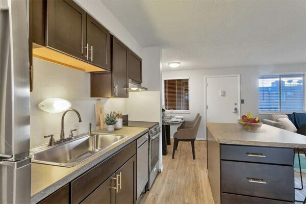 Kitchen with wood floor and cabinets, stone counters, and stainless steel appliances.
