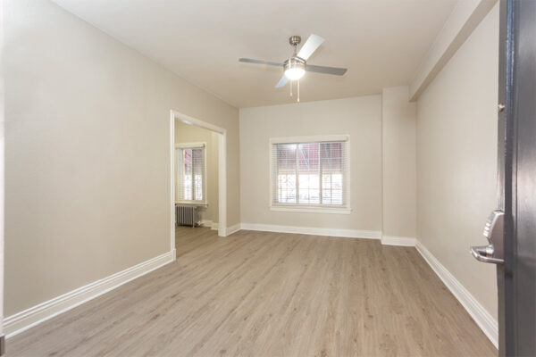 Living room with wood floor, tan walls, white trim, and ceiling fan.