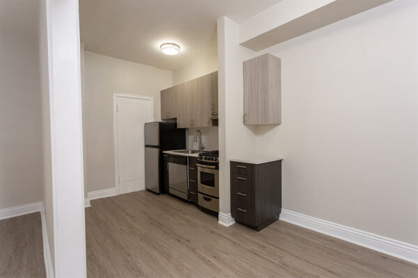 Kitchen with wood floor, dark cabinets, light counters, and stainless steel appliances.