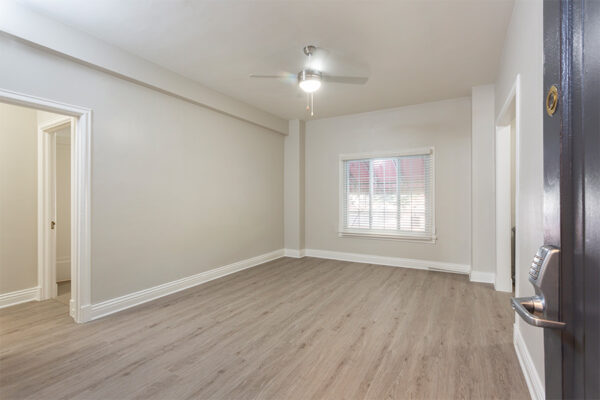 Living room with wood floor, warm gray walls, ceiling fan, and large window.