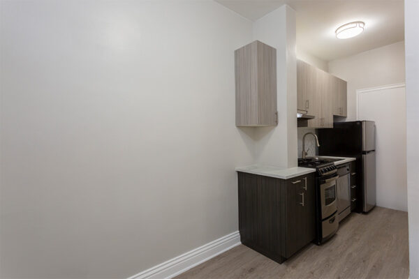 Kitchen with wood floor, dark cabinets, light counters, and stainless steel appliances.