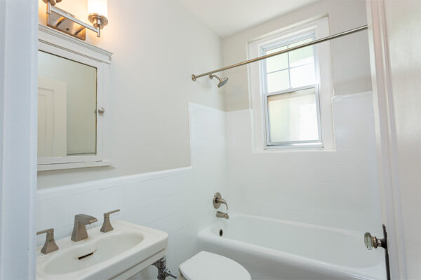 Bathroom with tiled shower tub, pedestal sink, and medicine cabinet.