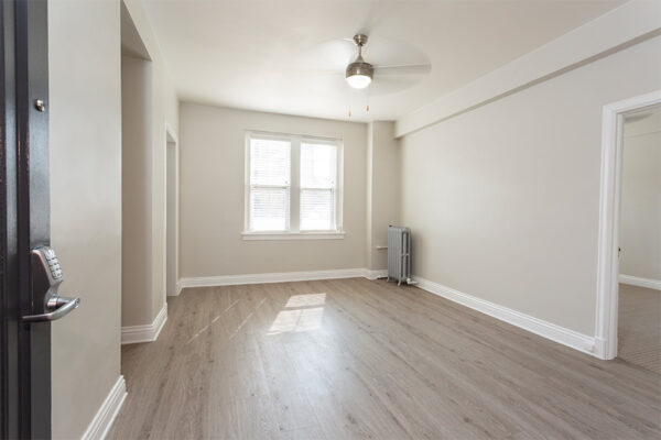 Living space with wood floors, warm gray walls, white trim, and ceiling fan.