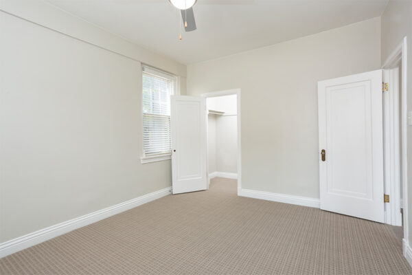 Bedroom with carpet, warm gray walls, white trim, ceiling fan, and large windows.