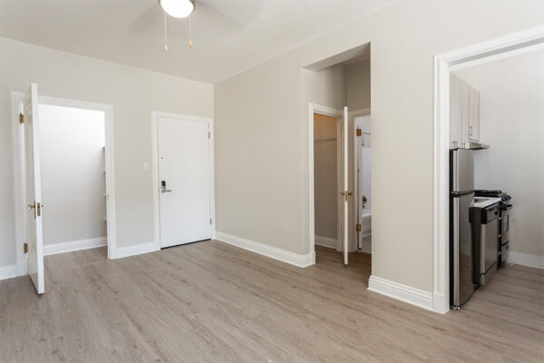 Living room with wood floor, warm gray walls, white trim, and doors to bathroom, closet and kitchen.