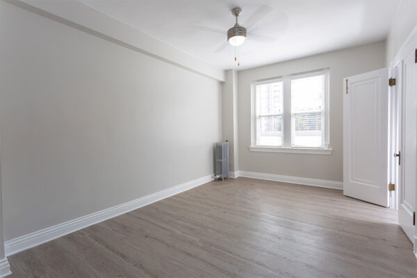 Bedroom with wood floor, warm gray walls, white trim, and large windows.