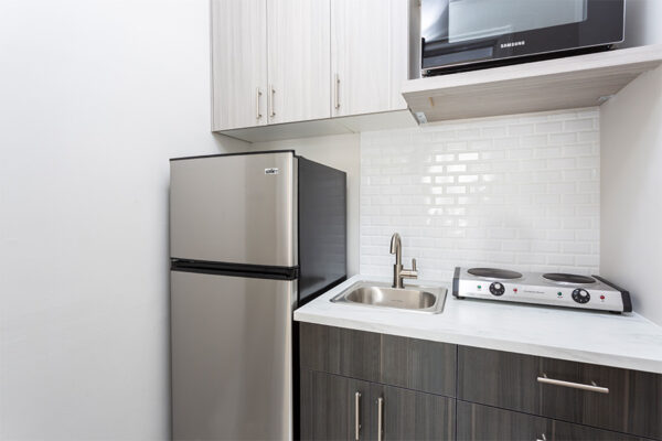 Kitchen with dark cabinets, light counters, stainless steel appliances, and tiled backsplash.