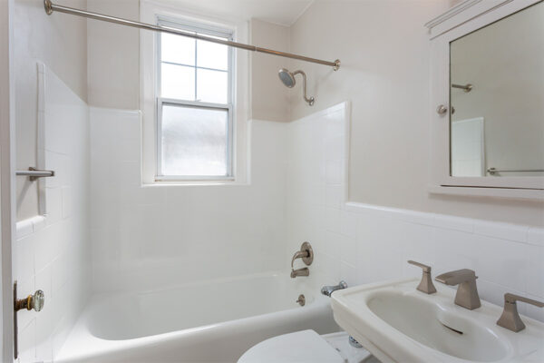 Bathroom with tiled shower tub, pedestal sink, and medicine cabinet.