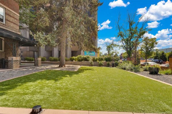 960 front lawn with lush green grass, rocky landscaping, and mature trees.