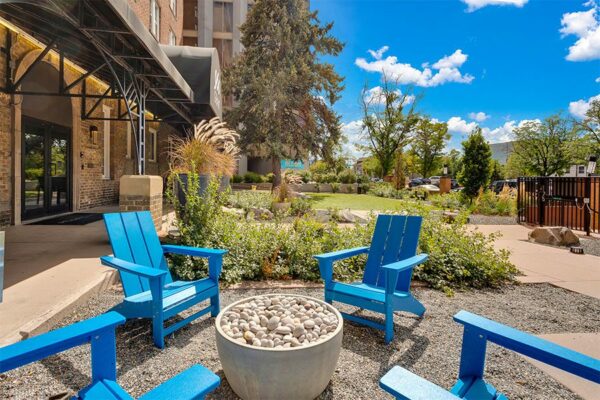 960 Grant patio with pavers, blue lounge chairs, lush landscaping, and tall trees.