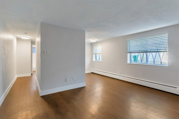 Living room with wood floor, baseboard heater, cool gray walls, and large windows.