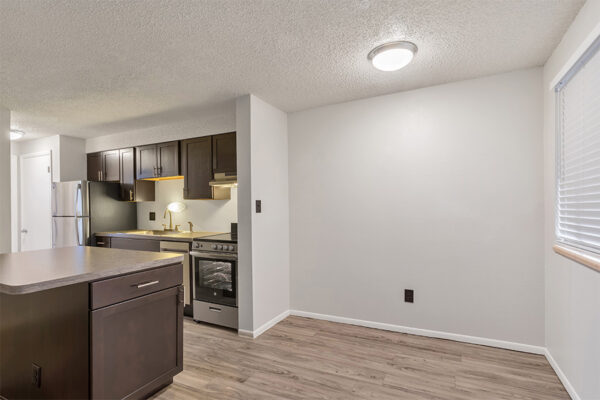 Living area with wood floor, cool gray walls, and kitchen with island.